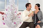 Paar feiert mit Sekt neben Weihnachtsbaum