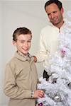 Père et fils à côté d'un arbre de Noël blanc