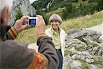 Senior adult man taking a picture of his wife in the mountains, selective focus