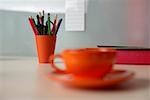 Cup of coffee next to to a cup with pencils