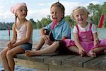 Three children each eating an ice lolly at a lake , close-up