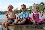 Three children each eating an ice lolly at a lake , close-up