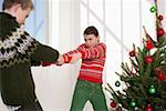 Girl and boy fighting for a Christmas present next to a Christmas tree