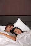 Young couple lying next to each other in bed sleeping