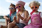 Three children with sunglasses each eating an ice lolly , close- up