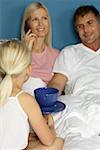 Little blond girl bringing a cup and a saucer to the bed of her parents, selective focus