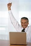 Cheering senior businessman using a laptop