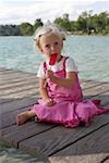 Little blond girl eating an ice lolly on a wooden footbridge