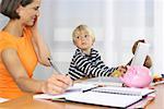 Mother phoning with a mobile phone and taking notes while son (4-5 Years) playing