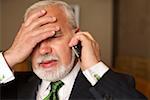 Despaired mature businessman phoning with a mobile phone