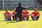 Joueurs de soccer à l'écoute de l'entraîneur