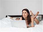 Woman Using Laptop Computer in Bed while Man Sleeps