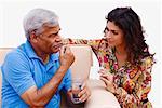 Senior man holding a pill with his granddaughter holding a blister pack beside him