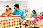 Couple assis à la table à manger avec leurs deux filles, assis derrière eux