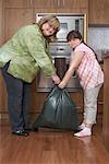 Mother and Daughter with Garbage Bag in Kitchen