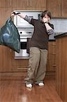 Boy with Garbage Bag in Kitchen