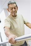 Low angle view of a physically challenged senior man walking on a treadmill