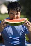 Young man biting a piece of a watermelon