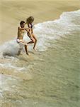 High angle view of a young couple running on the beach