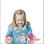 Close-up of a girl watching goldfish in a fishbowl