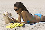 Profil d'une jeune femme lisant sur la plage
