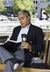 Businessman sitting on a bench with a flask