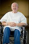 Patient masculin assis dans un fauteuil roulant avec ses mains jointes