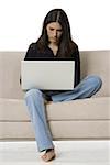 Young woman sitting on a couch and using a laptop