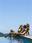 Profile of three young women relaxing by a pool