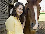 Portrait of a woman and a horse standing in front of a barn