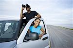 Young woman smiling with a young man looking through a pair of binoculars