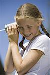 Low angle view of a girl listening into a tin can phone