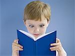 Boy reading harcover book cross eyed
