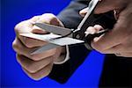 Close-up of a person's hand cutting a credit card with a pair of scissors