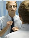 Close-up of a young man putting on a tie