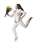 Young woman jumping in mid-air and holding a bouquet of flowers