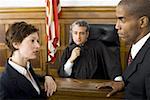 Two lawyers standing face to face in front of a male judge in a courtroom