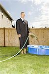 Businessman filling a wading pool with water