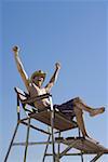 Low angle view of a young man sitting on a lifeguard chair