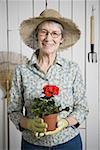 Portrait of an elderly woman holding a potted plant