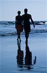 Rear view of a mid adult couple holding hands and walking on the beach