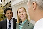 Close-up of a businesswoman and two businessmen smiling