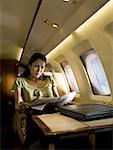 Femme d'affaires assis dans un avion et lire un journal
