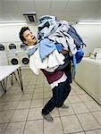 Mann mit einem Haufen von Kleidung im Waschsalon