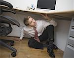 Portrait of a businessman hiding under a desk