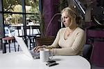 Junge Frau mit einem Laptop in einem café