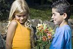 Voir le profil:: un garçon donnant des fleurs à une jeune fille et souriant