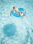 Young boy floating on life ring in swimming pool