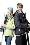 Adolescente et garçon avec des manteaux d'hiver et les skis souriant