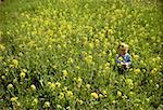 High angle view of a toddler sitting in a field of flowers